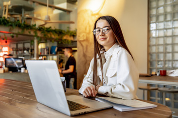 Beautiful brunette browsing internet on personal laptop