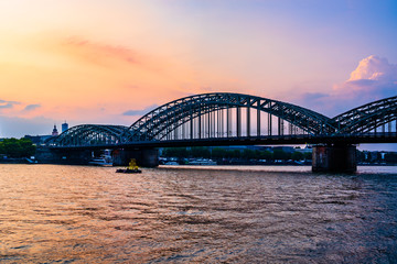 Fototapeta na wymiar Sunset silhouette skyline landscape of the gothic Cologne Cathedra, Hohenzollern railway and pedestrian bridge, the old town and Great St Martin church on the banks of river Rhine in Cologne, Germany