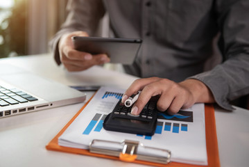 Fototapeta premium Businessman or accountant working on laptop computer and tablet with business document, graph diagram and calculator on office table in office.