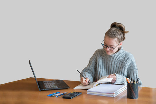 Young caucasian girl studying with online lesson on the laptop at home. Desk with white background space for text. Smart school education concept
