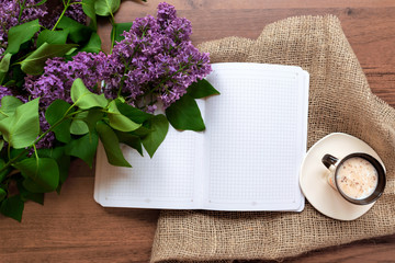 desk with lilac,  notebook and cup of coffee