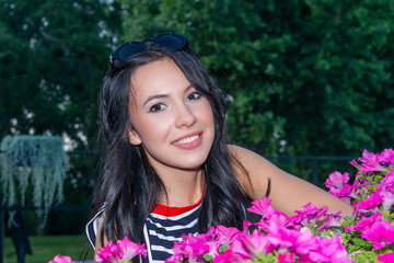 Young woman standing near with beautiful flowering petunias outdoors