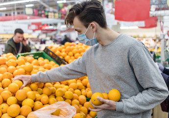 Obraz premium Young man wearing disposable medical mask shopping in supermarket during coronavirus