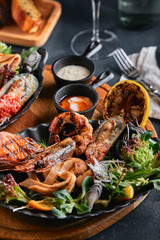 Assorted seafood on plates. Beautiful composition on a served seafood table, squid, shrimp, salmon steak and octopus. Food photo, low key, traditional Italian cuisine. Top view, save the space