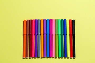 multicolored markers for drawing on a yellow paper background