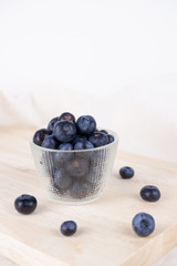 Fresh Blueberry in bowl with spoon and folk on wooden plate