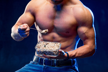 Muscular bodybuilder eating healthy cereal. Healthy lifestyle concept. Naked torso athlete on a...