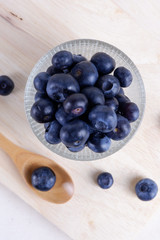 Fresh Blueberry in bowl with spoon and folk on wooden plate