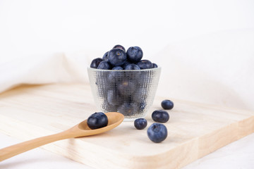 Fresh Blueberry in bowl with spoon and folk on wooden plate