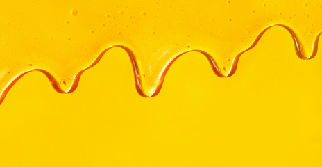 Flow of sweet honey on the yellow background