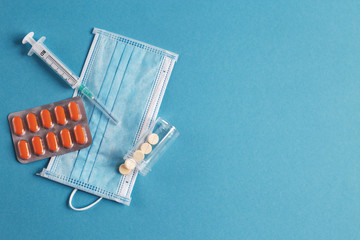 medical mask, syringe, tablets and vials with medicine on the blue background. Coronavirus, flu, disease concept.