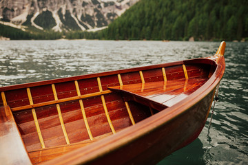 Obraz premium Lake Braies, wooden boat on a mountain lake, nature and travel. Wooden boat at Lago di Braies. Tourist boat near old wooden dock house with pier on emerald surface lake water of Lago di Braies.