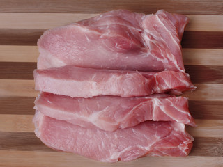 Sliced pieces of raw meat on a wooden board, top view