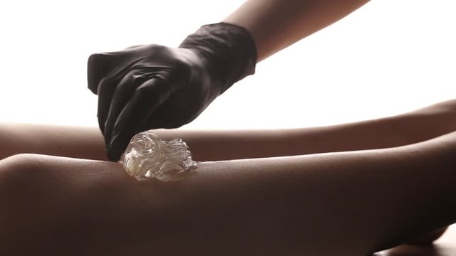 Shugaring with the help of pasta for a woman. Woman's legs in the studio on a white background. Depilation, getting rid of leg hair.