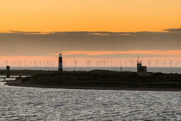Spurn Heritage Coast, UK - 2016 JULY 03. Lighthouse at Spurn Point with orange skye and windfarm in the background.