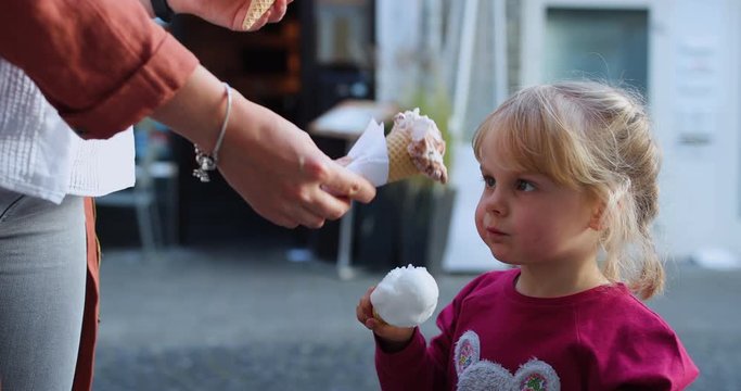Little blond girl eating eis in the pink
