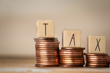 Wooden cubes with the word Tax on money climbing staits, pile of coins ,Tax Concept background