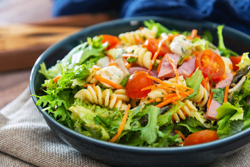 Salad with fusilli pasta accompanied tomatoes, mozzarella, smoked ham and italian cheese