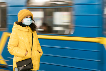 The young europeans woman in protective disposable medical face mask in the subway. New coronavirus (COVID-19).