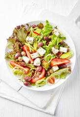 Healthy salad with feta cheese, various olives, leek and tomatoes. White wooden background. Top view.