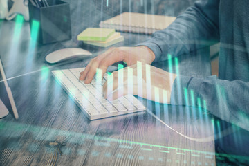 Stock graph with businessman typing on computer in office on background. Concept of analysis. Double exposure.