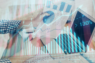 Double exposure of stock graph with businessman typing on computer in office on background. Concept...
