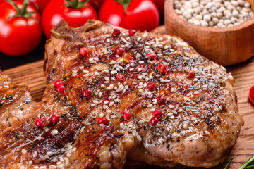 Fresh delicious juicy steak on the bones with vegetables and spices against a dark background