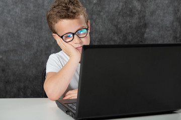 serious boy sitting with laptop computer