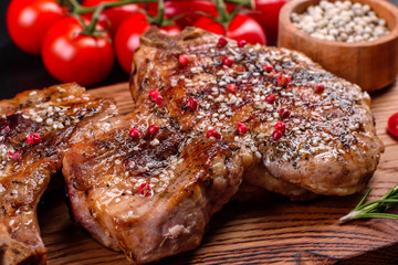 Fresh delicious juicy steak on the bones with vegetables and spices against a dark background