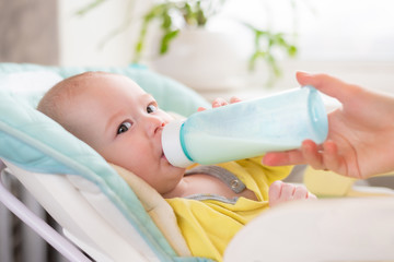 Mother feeds the baby. The toddler drinks milk from a bottle .