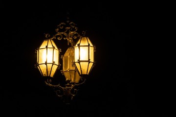 Fototapeta na wymiar Historical lamp post in Valletta, Malta with three bulbs, two of them are shining in darkness