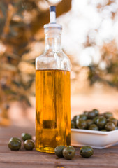 green olives and oil on table in olive grove