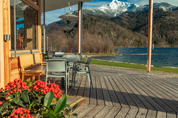 Fototapeta premium patio restaurant outside porch space empty table without people flowers foreground with scenic picturesque background view on Alps mountains
