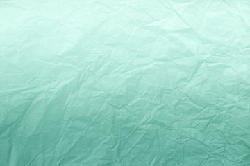 Texture of crumpled green wrapping paper with white gradient, closeup. Light cyan old background.