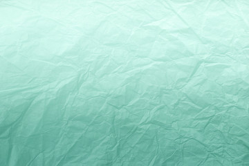 Obraz premium Texture of crumpled green wrapping paper with white gradient, closeup. Light cyan old background.