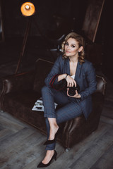 Fototapeta na wymiar Portrait of a confident beautiful business woman in a suit on a dark background holds a camera in her hands. The concept of gender equality. Strong independent woman. Soft selective focus.