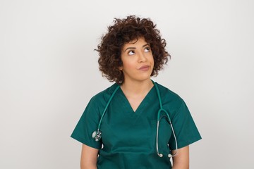 Gloomy, wondering young doctor woman looking up, being upset thinking about something important,...