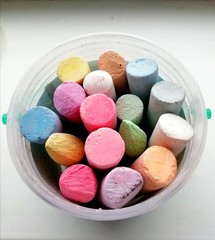 Children's colored crayons in a bank on a white background.