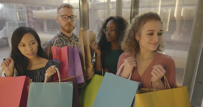 Young people riding glass elevator in shopping mall
