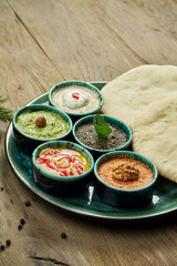 Classic eastern snacks with pita - meze. Set in small bowl - Hummus, hot pepper paste often with walnuts, yogurt, eggplant paste.