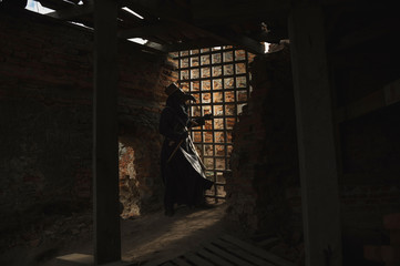 A man in historical masquerade costume of plague doctor in old gothic grange building of church....
