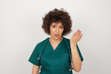 What the hell are you talking about, nonsense. Studio shot of frustrated doctor female gesturing with raised palm, frowning, being displeased and confused with dumb question over gray wall.