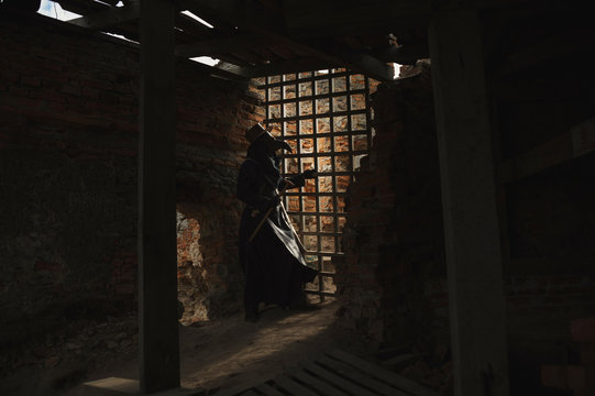A man in historical masquerade costume of plague doctor in old gothic grange building of church. Epidemia protection costume. Pandemia horror mystical fantasy plague doctor