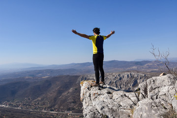 Man rise a hands on top of the mountain. Concept of freedom. Young man enjoy on a cliff edge
