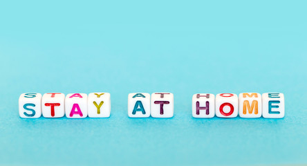 Phrase Stay At Home made out of colorful beads on blue background