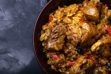 Large portion of pilaf in a clay dish. Delicious uzbek homemade meal. Toned