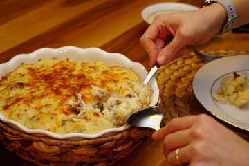 Cauliflower with bechamel sauce and melted cheese on top in ceramic dish with straw mat cover