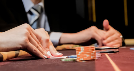 Dealer sitting in a casino at table while holding and distributing cards