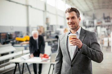 Young businessman drinking coffee in fatory.