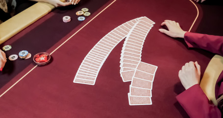 Dealer sitting in a casino at table while holding and distributing cards